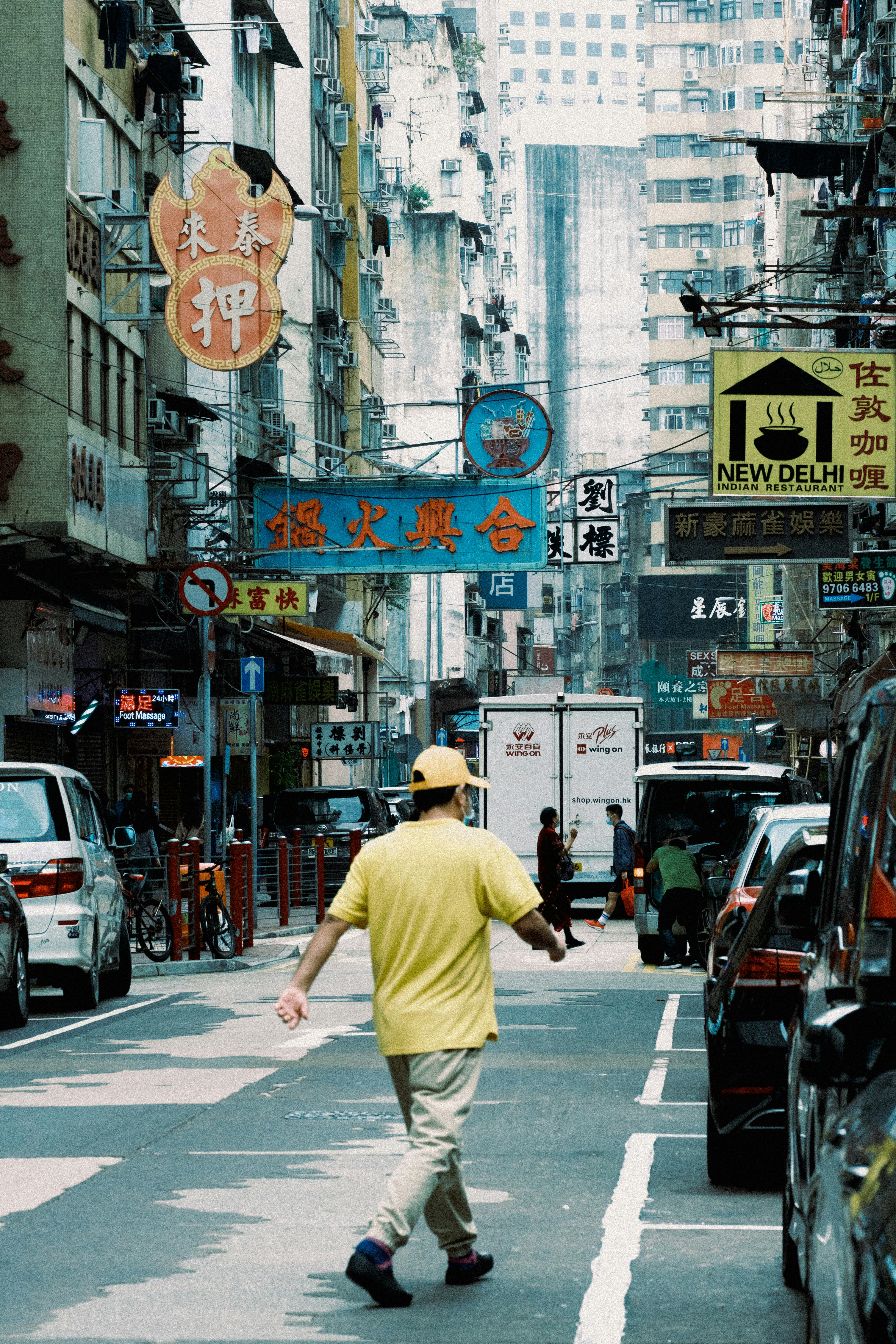 man in yellow shirt and brown pants walking on pedestrian lane during daytime