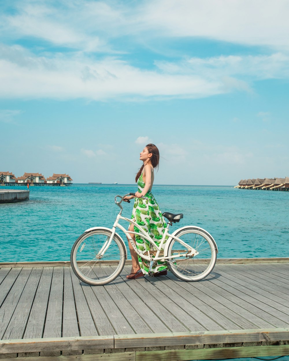 woman in black tank top and green shorts riding on bicycle on dock during daytime