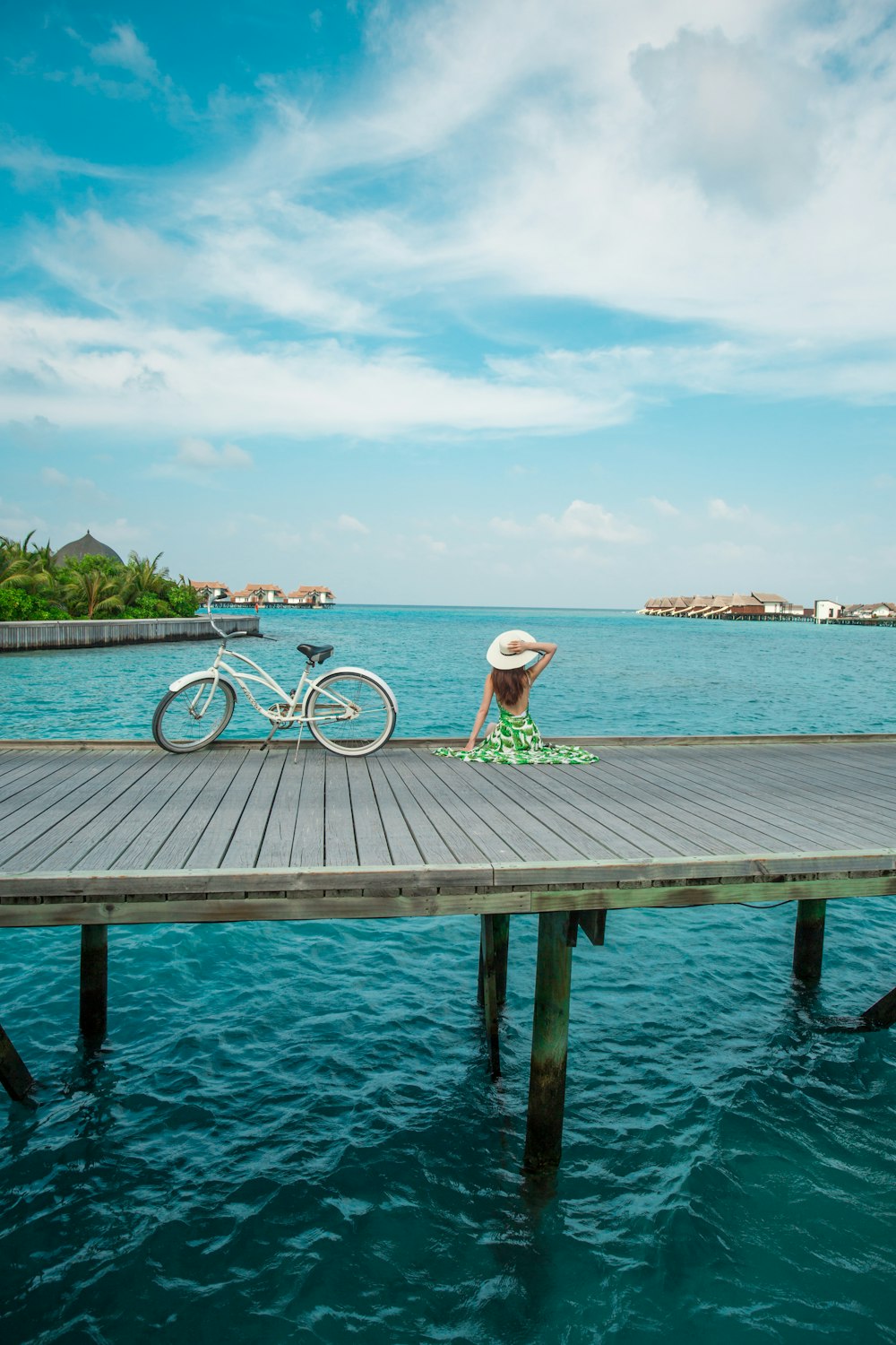 woman in white bikini sitting on brown wooden dock near body of water during daytime