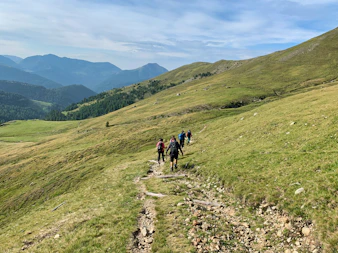 people hiking on green grass field during daytime