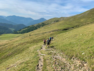 people hiking on green grass field during daytime