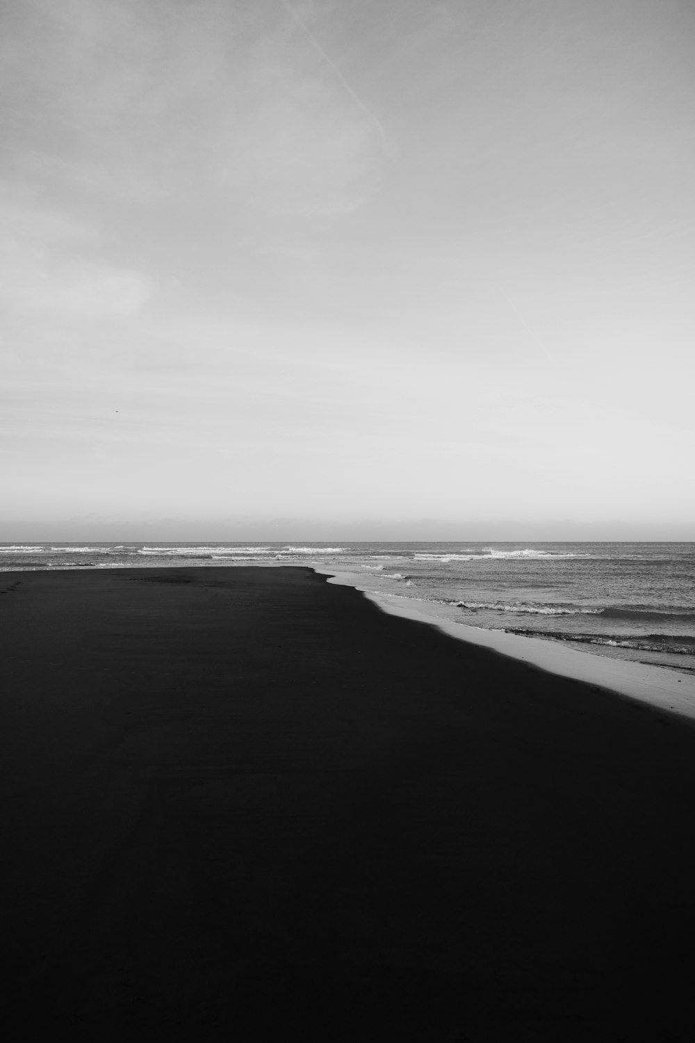 grayscale photo of beach under cloudy sky