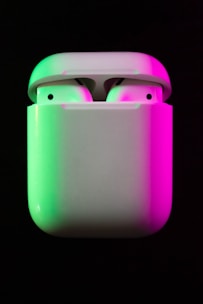 A pair of wireless earbuds glowing softly against a dark background.