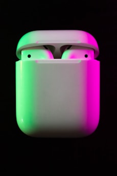 A pair of wireless earbuds glowing softly against a dark background.