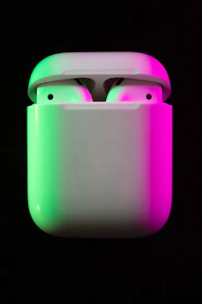 Close-up of a neon blue silicone AirPods cover glowing softly against a dark background.