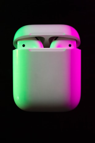 A pair of wireless pink earbuds resting on a matching charging case with subtle LED lights.