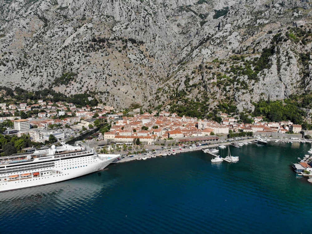 white cruise ship on body of water near mountain during daytime
