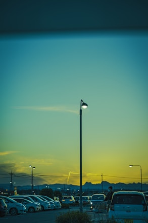 A modern parking lot with automated barriers and digital payment kiosks at sunset.