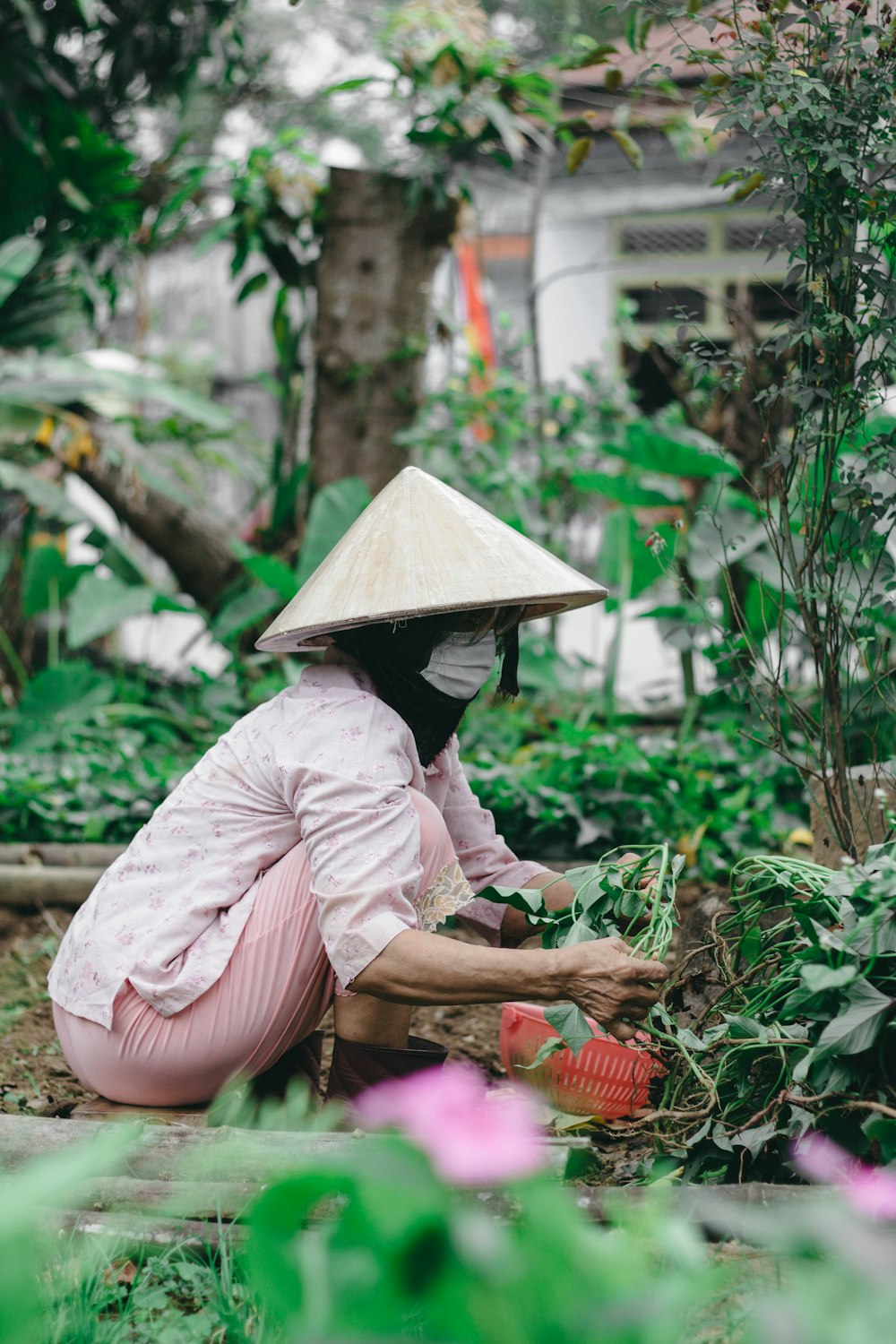 woman in pink long sleeve shirt and white hat sitting on ground