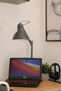 A minimalist workspace with sleek black and white decor, featuring a laptop, a plant, and soft natural light.