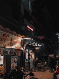A lively urban night scene with diverse people meeting and chatting at a cozy outdoor café.
