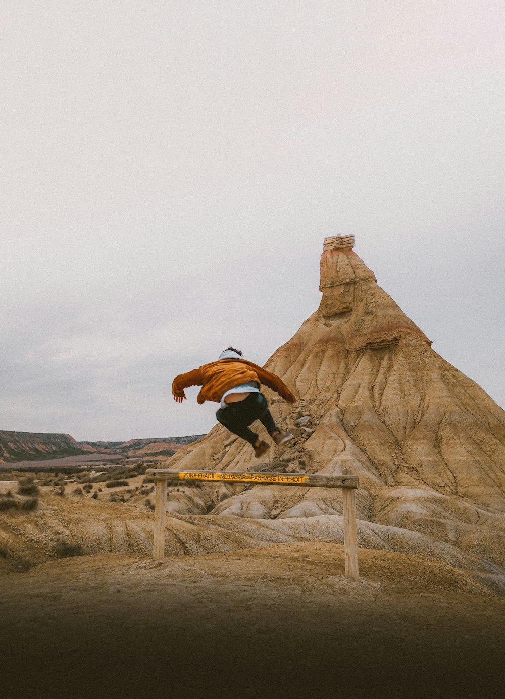 man in black jacket and black pants jumping on brown wooden pole during daytime