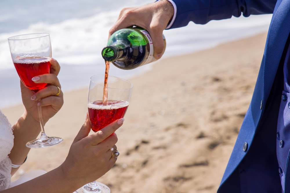 2 person holding drinking glasses on beach during daytime