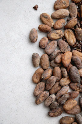 Artisanal cacao beans spilling from a rustic wooden bowl.