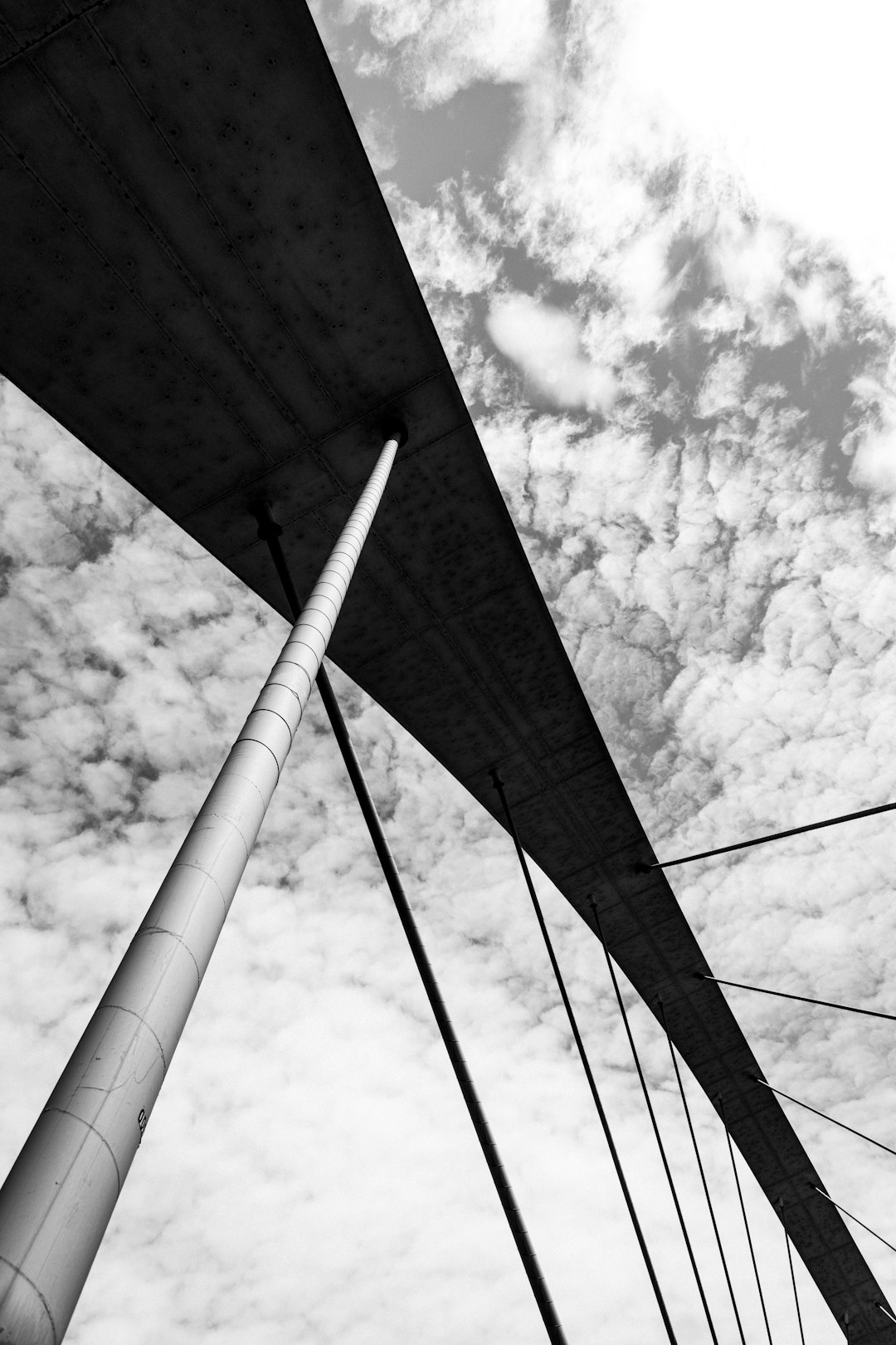 grayscale photo of bridge under cloudy sky