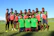 A happy group of club members proudly wearing their custom-designed jerseys outdoors.