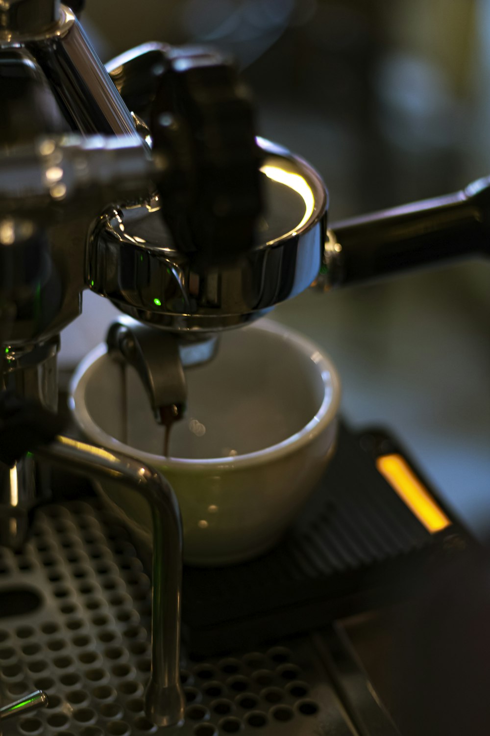 white ceramic teacup on black and silver espresso machine