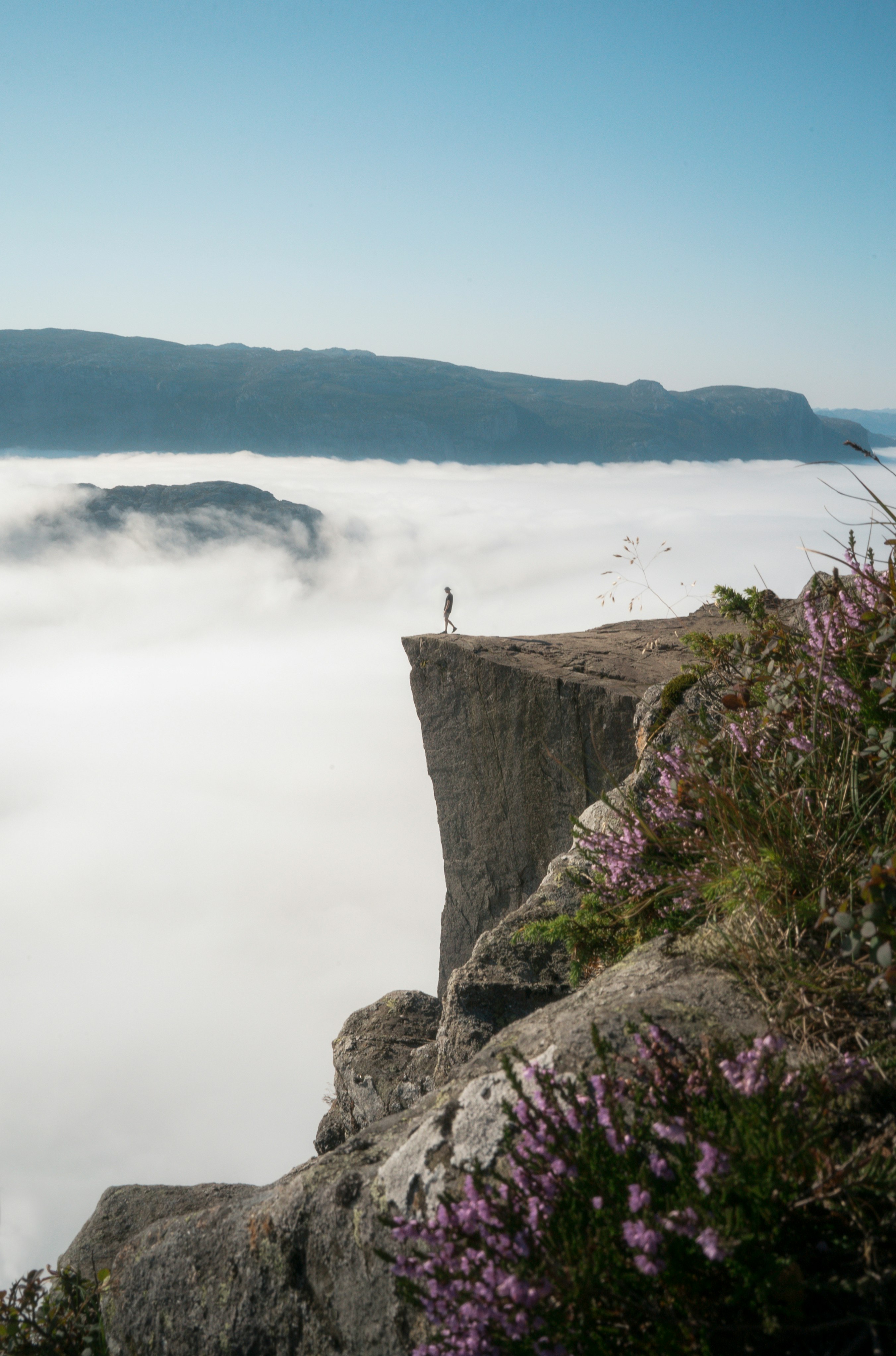 person standing on cliff near body of water during daytime