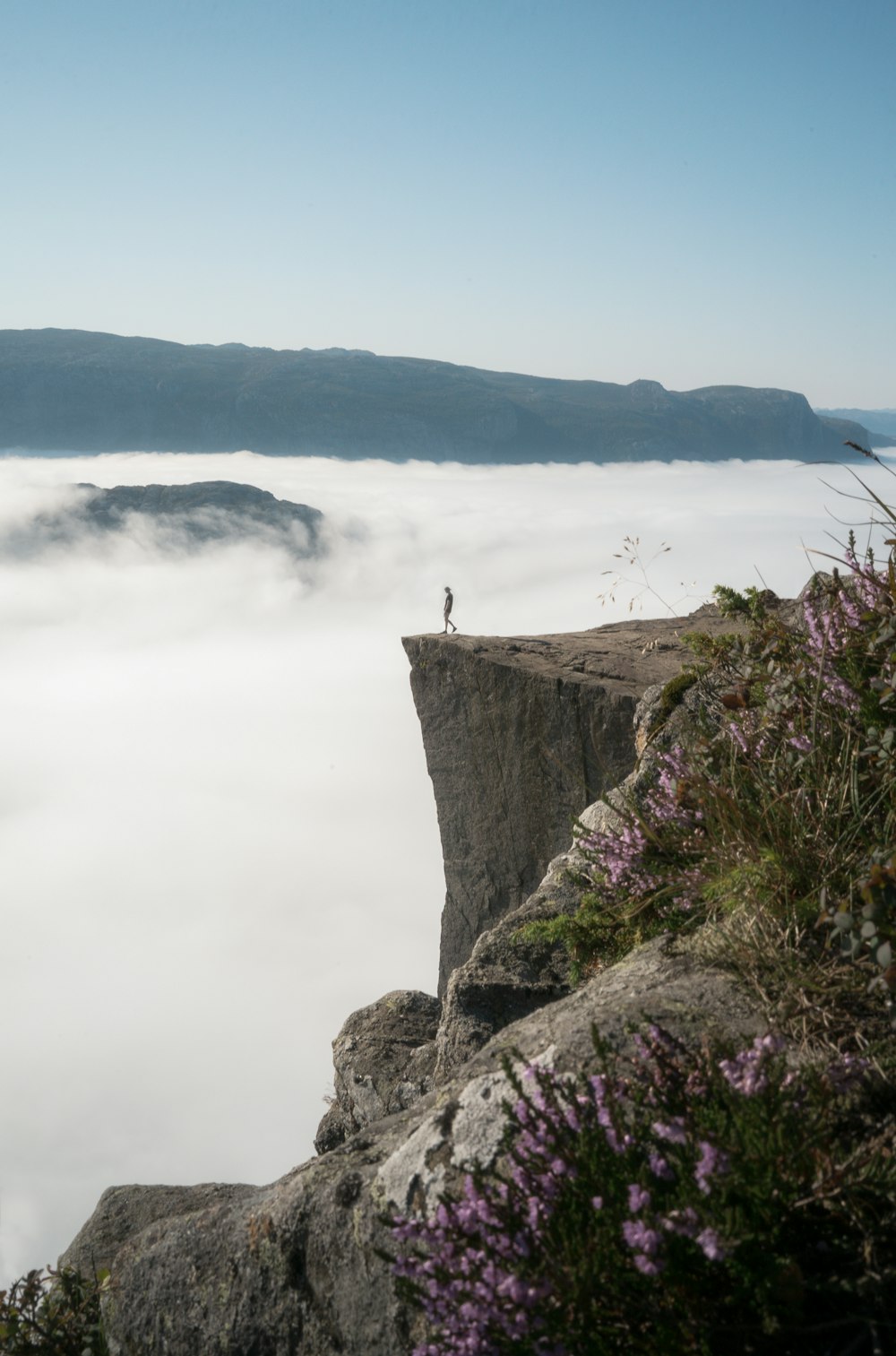 Person, die tagsüber auf einer Klippe in der Nähe eines Gewässers steht