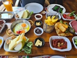 A colorful spread of breakfast items including eggs, bread, and fresh vegetables on a table