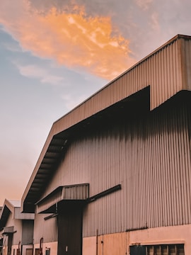 Wide-angle view showing a large industrial shed with vibrant color-coated steel roofing shining in the sunlight.