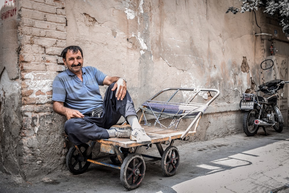 homme en chemise bleue assis sur un fauteuil roulant noir