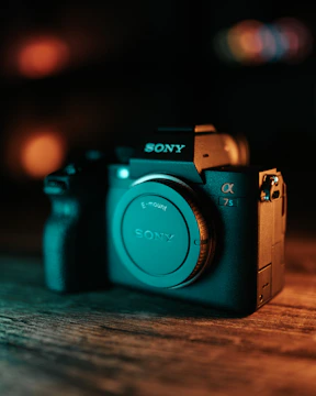 Close-up of a Sony cinema camera with a sleek lens against a dark moody background.