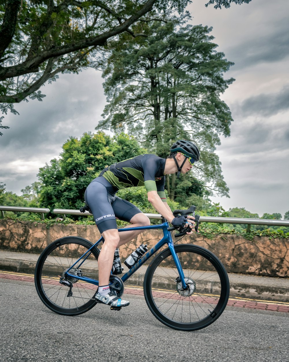 man in black shirt and black shorts riding blue mountain bike