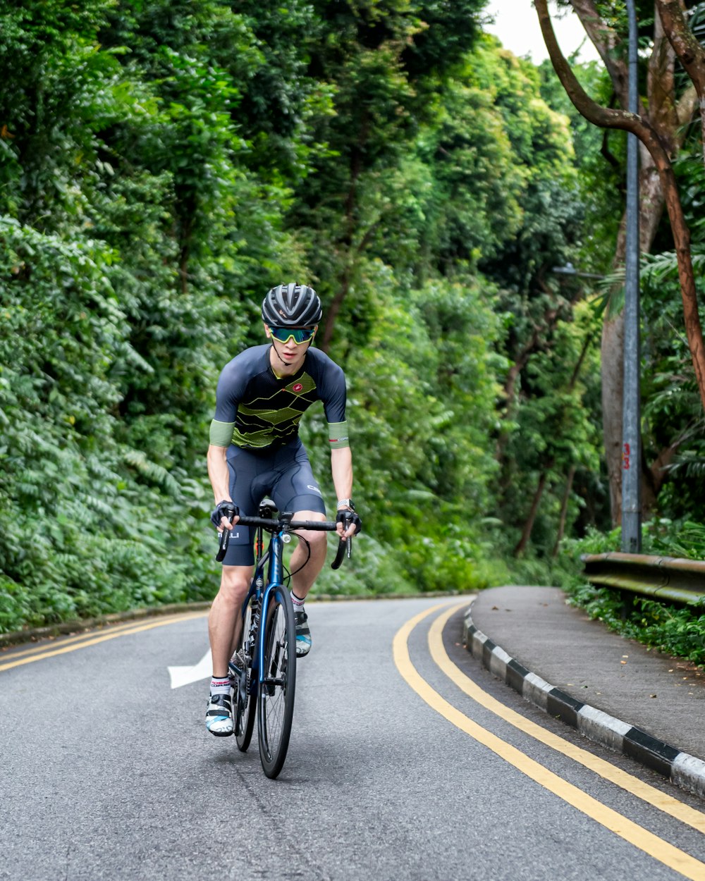 昼間、道路を自転車で走る黒いシャツの男