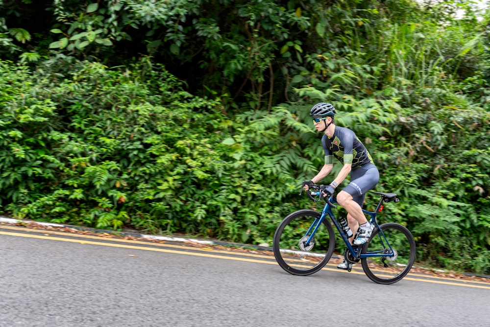 man in gray shirt riding on blue bicycle during daytime