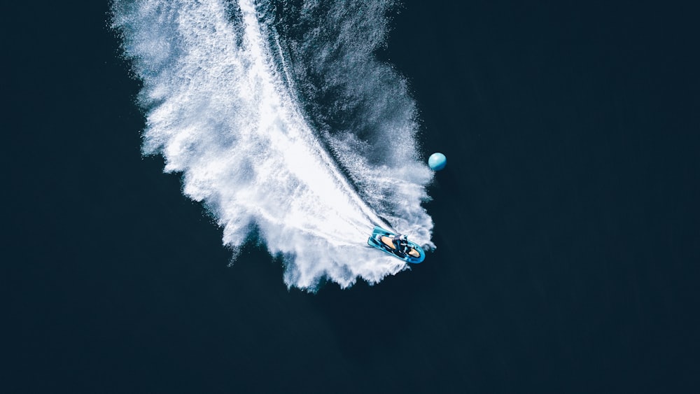 Persona con sudadera con capucha azul y blanca montando en un bote azul y blanco en el agua