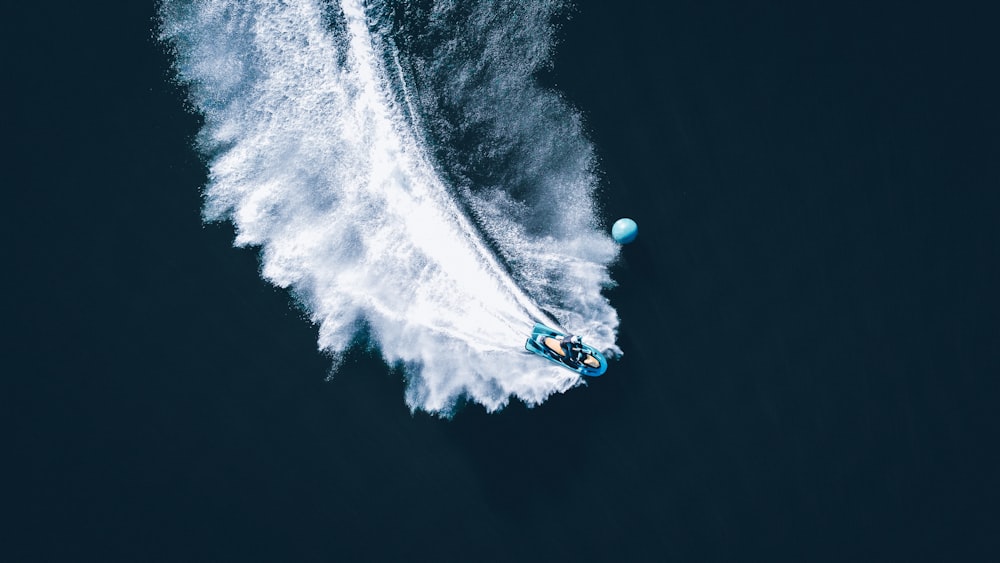 person in blue and white hoodie riding on blue and white boat on water