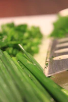Close-up of a student skillfully chopping fresh herbs for a Thai curry.