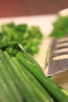 A chef’s knife slicing through fresh herbs on a rustic cutting board.