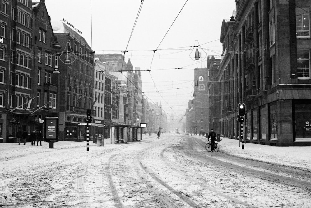 grayscale photo of people walking on street between buildings