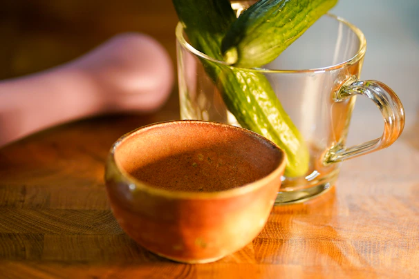 A rustic ceramic bowl with a textured glaze sitting on a wooden table bathed in natural light