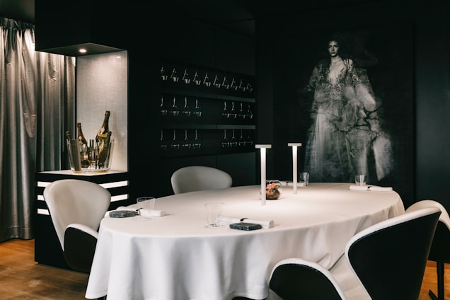 Elegant dining room with black matte walls, golden accents, and cream-colored table settings under soft lighting
