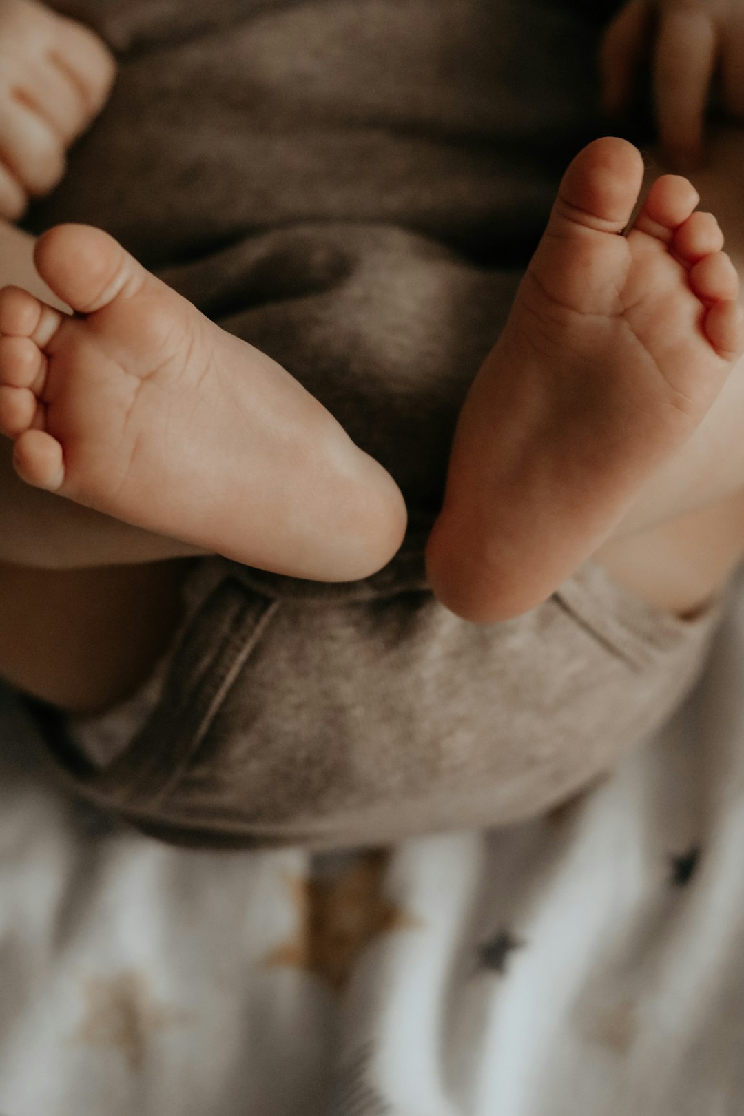 babys feet on gray textile