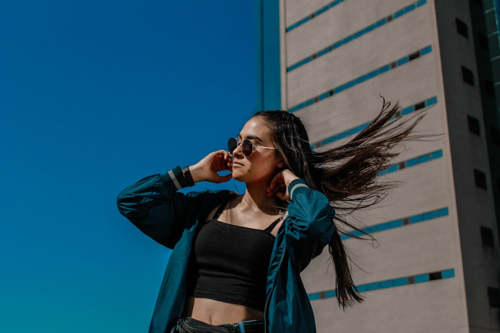 woman in black crop top and blue jacket wearing black sunglasses