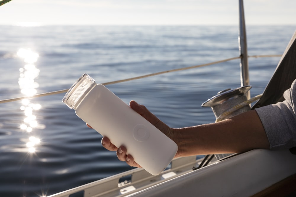 白いプラスチックのコップを持っている人