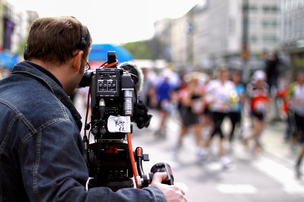 man in gray hoodie holding black and red video camera