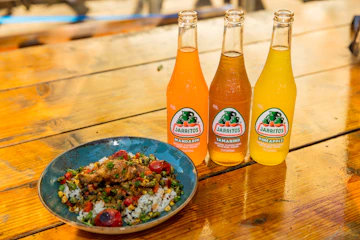 two orange soda bottles beside blue ceramic bowl with food