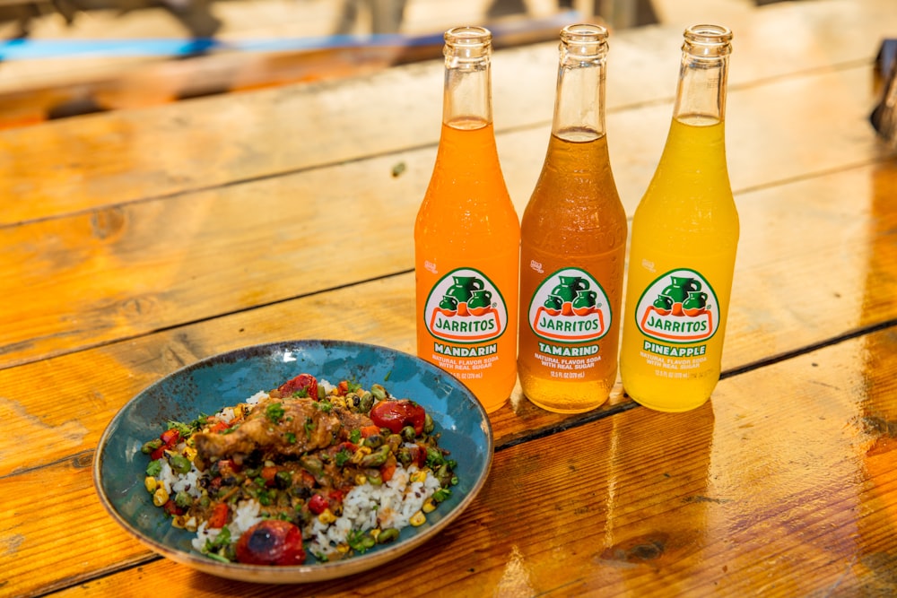 two orange soda bottles beside blue ceramic bowl with food