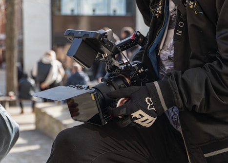 man in black and white jacket holding black video camera