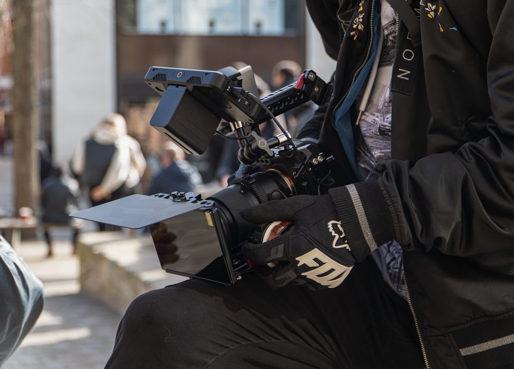 man in black and white jacket holding black video camera