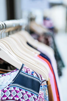 A vibrant display of children's and women's clothing hanging on a rustic wooden rack, showcasing bright colors and soft fabrics.