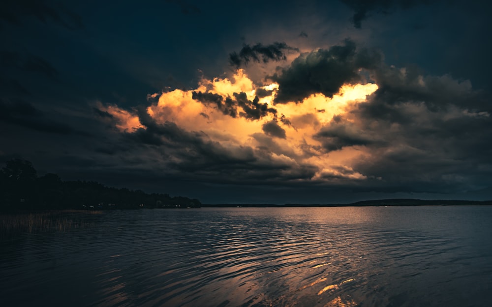 corpo d'acqua sotto cielo nuvoloso durante il tramonto