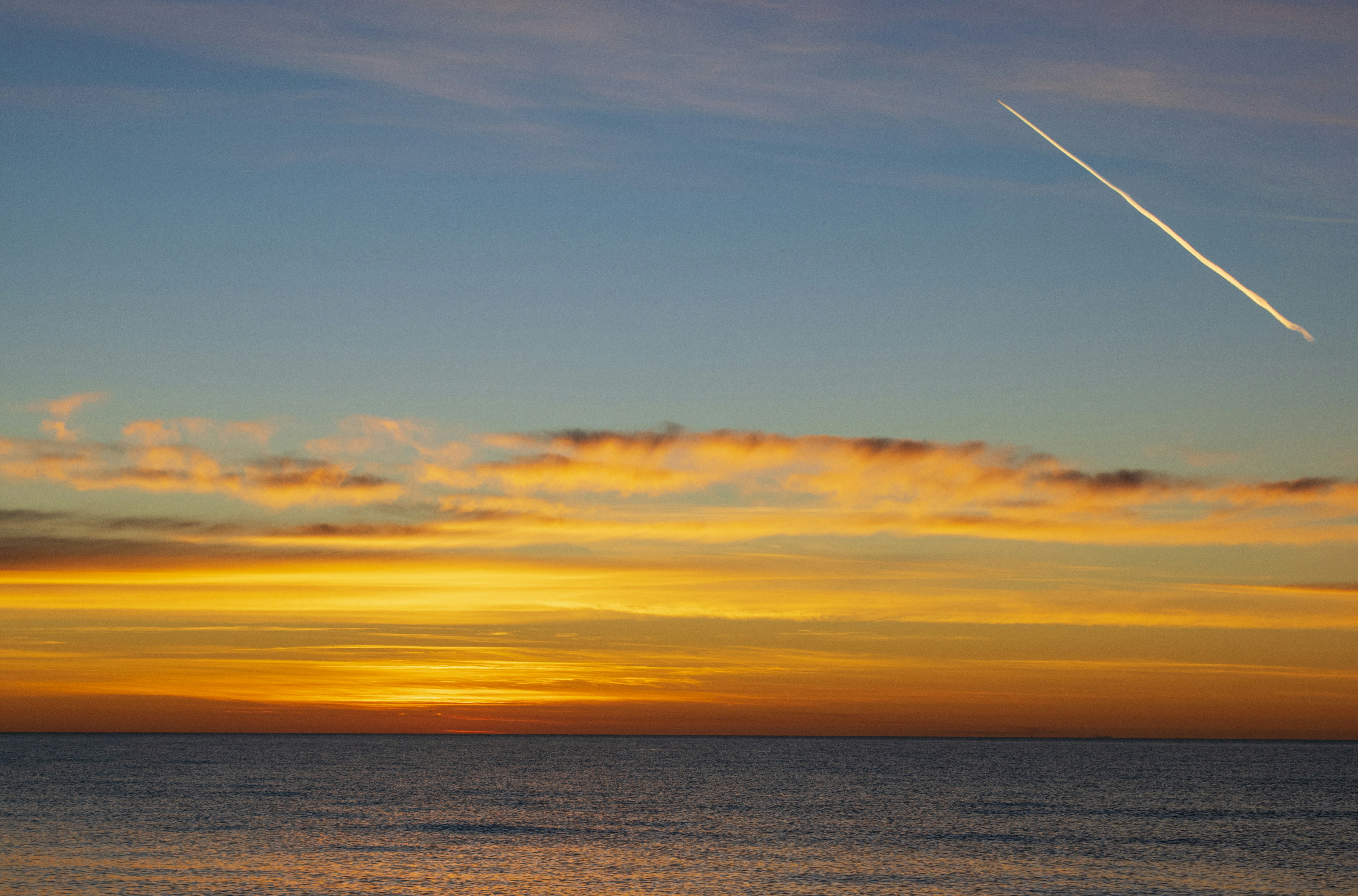 日没時のオレンジ色の空の下の水域