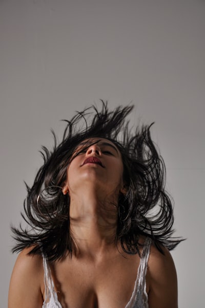 a woman flipping her hair while wearing a hair topper