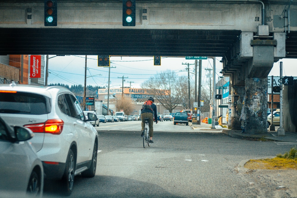 man in black jacket riding bicycle on road during daytime